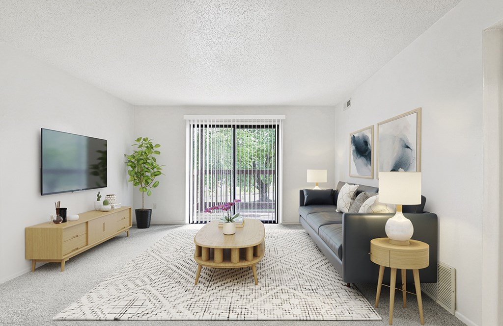 A living room with a couch, a wooden coffee table, and a flat-screen TV mounted on the wall at Old Monterey Apartments in Springfield, MO