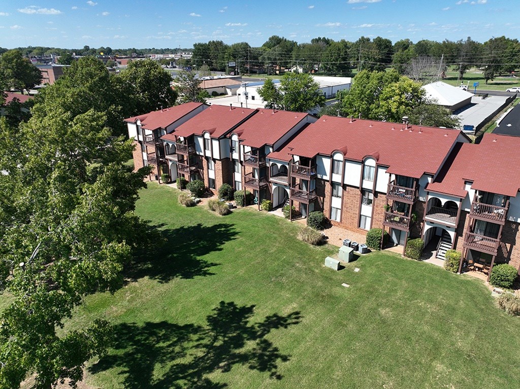 A large building with a red roof is surrounded by green grounds at Old Monterey Apartments, Springfield, MO