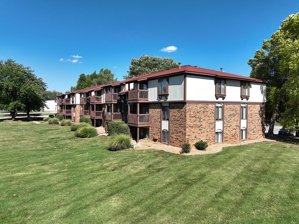 A brick building with a red roof and white exterior walls with windows and balconies at Old Monterey Apartments, Springfield, MO