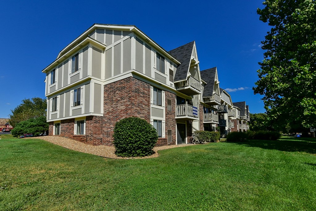 A large building with a brick base and white siding at Old Monterey Apartments, Springfield, MO