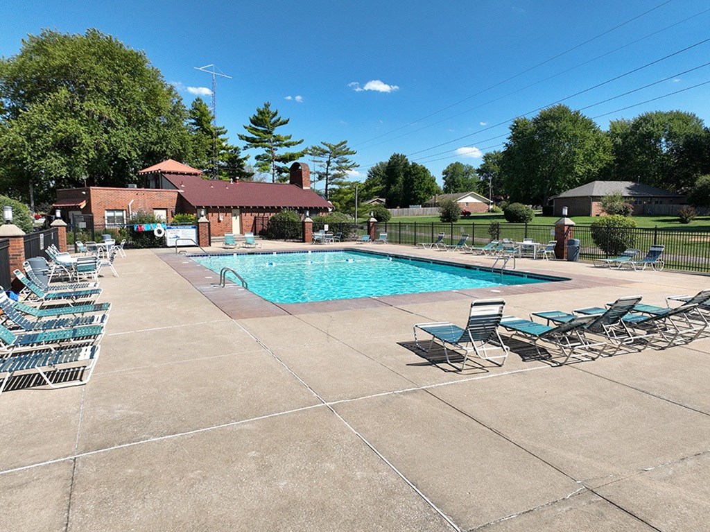 A pool surrounded by chairs and a building in the background at Old Monterey Apartments, Springfield, MO