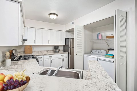 A kitchen with a marble counter top and white cabinets.