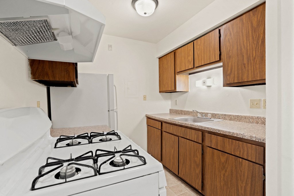 a kitchen with a white stove top oven next to a sink and a refrigerator at Beacon Hill and Great Oaks Apartments, Rockford