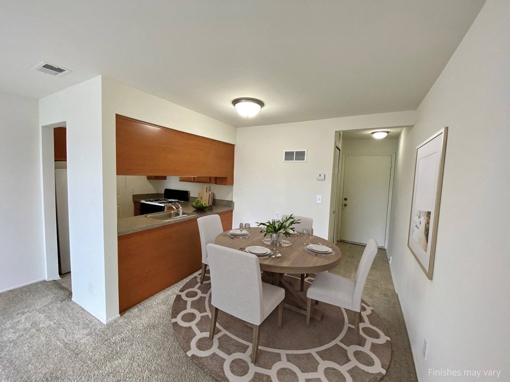 a dining area with a table and chairs and a kitchen in the background at The Landings Apartments, Westland, MI