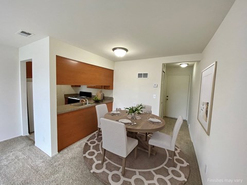 a dining area with a table and chairs and a kitchen in the background