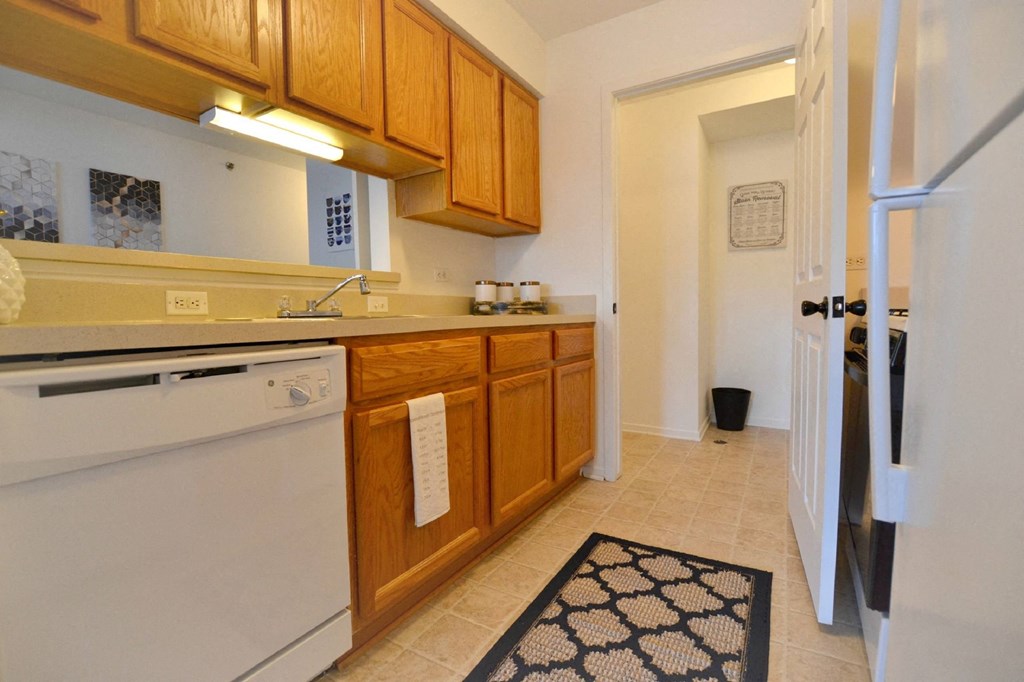 a kitchen with wooden cabinets and a white dishwasher  at Northport Apartments, Michigan