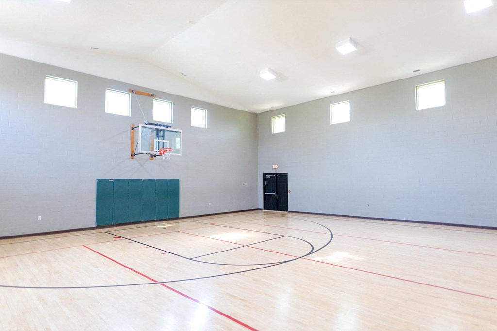 an empty gym with a basketball hoop and a door at Latitudes Apartments, Indiana