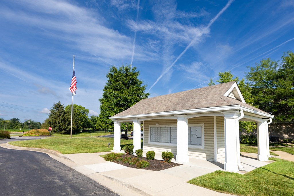 a small white building with a flag on a pole in front of it at Latitudes Apartments, Indianapolis, IN