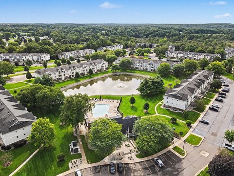 A bird's eye view of an apartment community with a swimming pool and a parking lot at Pine Knoll Apartments, Battle Creek