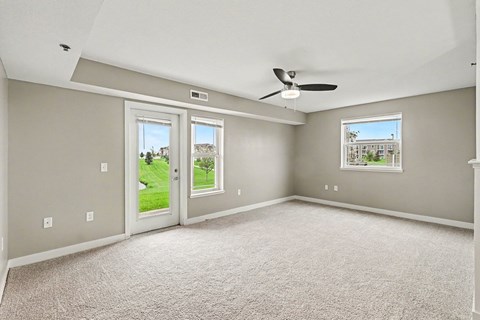 An enlarged living room with a carpeted floor and a ceiling fan at The Reserve at The Reserve at Destination Pointe in Grimes, IA 50111