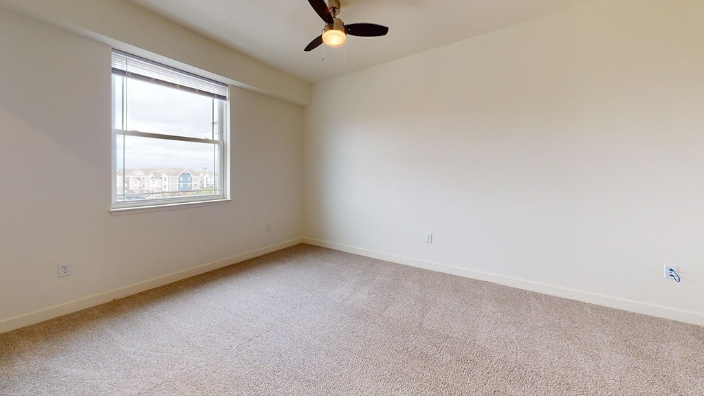 A bedroom with a ceiling fan and a window at The Reserve at Destination Pointe apartments, Grimes, IA