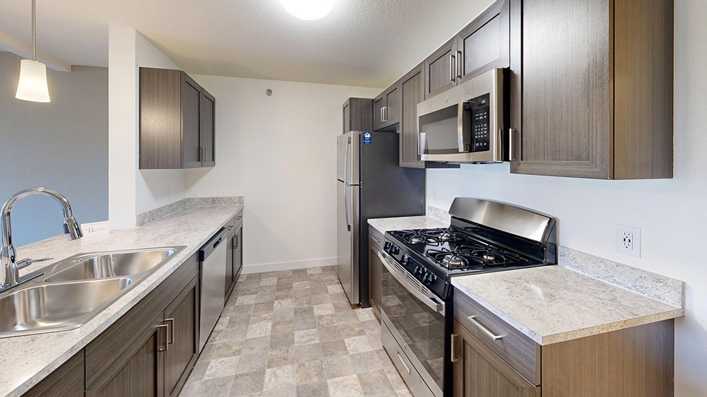 A kitchen with a stove, sink, and refrigerator at The Reserve at Destination Pointe apartments, Grimes, IA