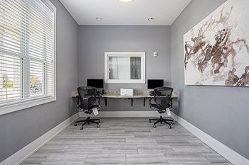 A business center with two black chairs are placed in front of a desk with a computer at The Reserve at Destination Pointe apartments, Grimes, IA 50111