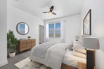 A bedroom with a bed, a ceiling fan, and a potted plant at The Reserve at Destination Pointe apartments, Grimes, IA