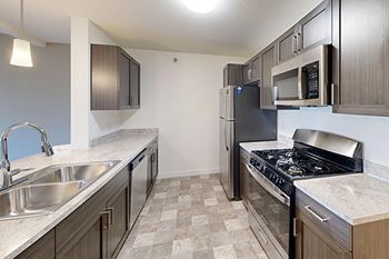 A kitchen with a breakfast bar and stainless-steel appliances at The Reserve at Destination Pointe, Grimes, IA