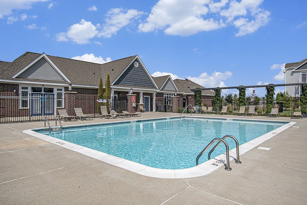 A swimming pool in front of a building with a fence around it at The Reserve at The Reserve at Destination Pointe in Grimes, IA 50111