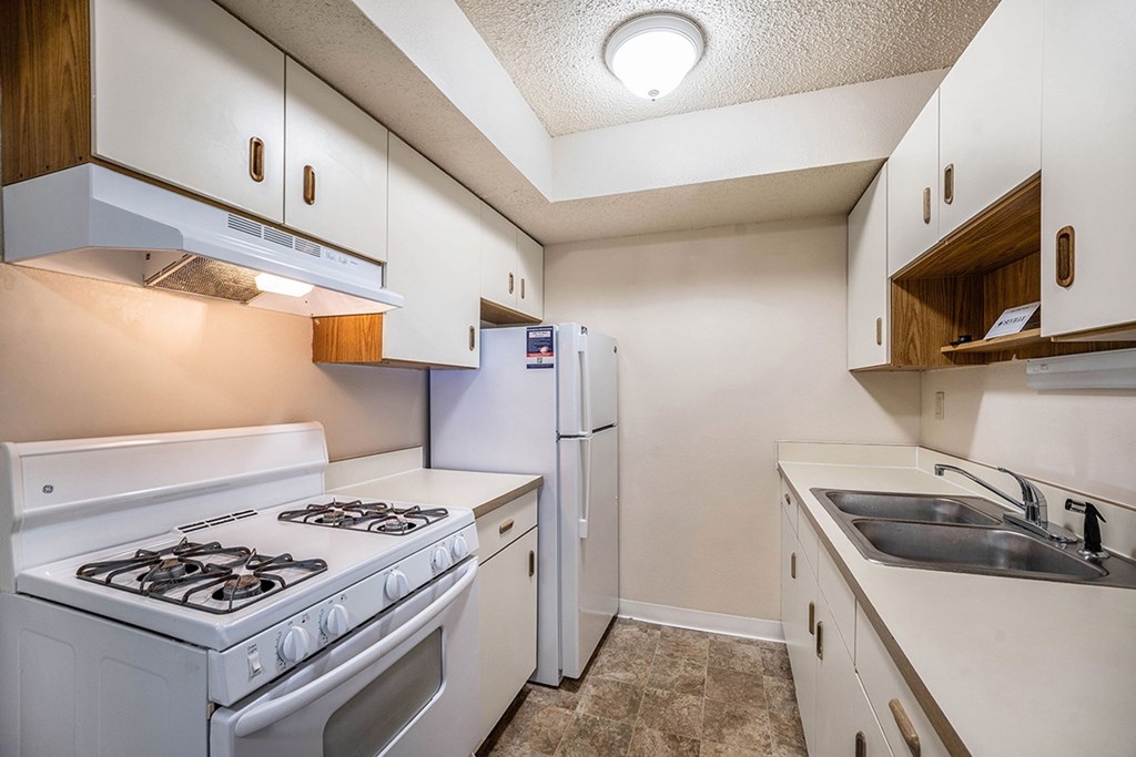 A galley-style kitchen with a white stove and refrigerator at Seville Apartments, Michigan
