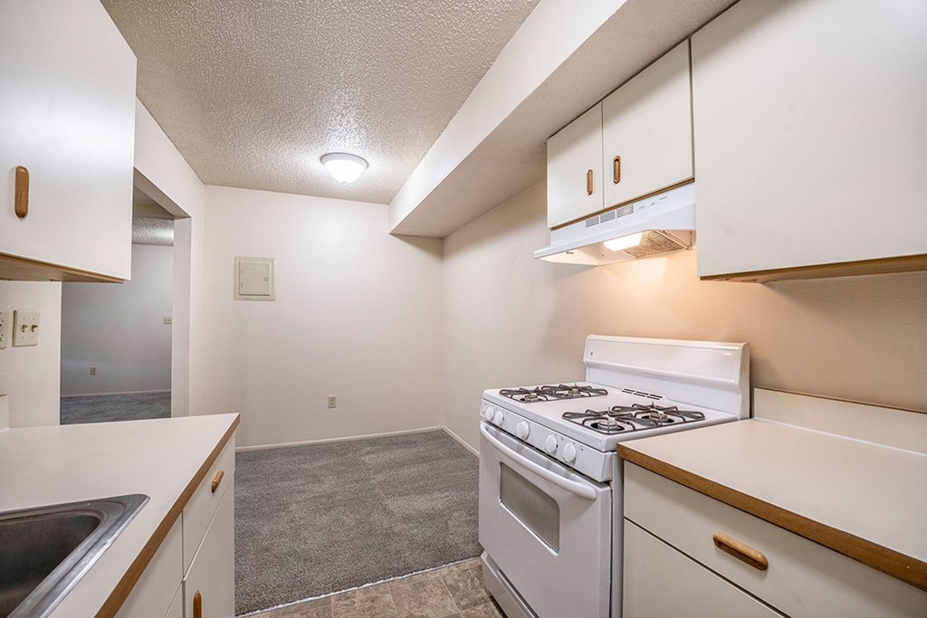 A kitchen with a white stove top oven leading to a dining room at Seville Apartments, Michigan