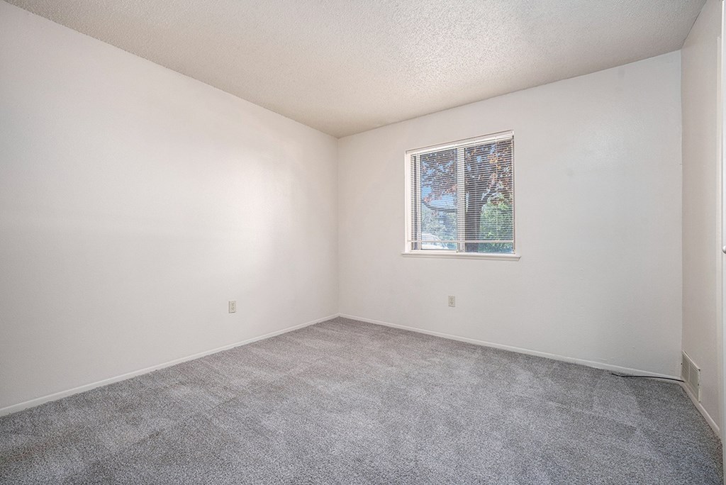 A bedroom with a window and carpeted floor at Seville Apartments, Michigan