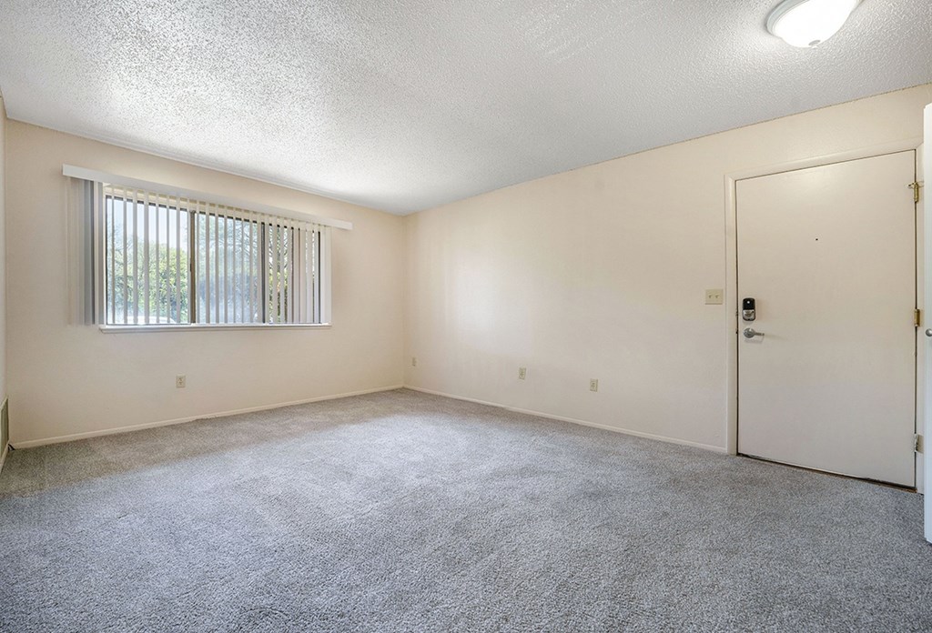 A garden style living room with a window with blinds and plush carpeting at Seville Apartments, Michigan