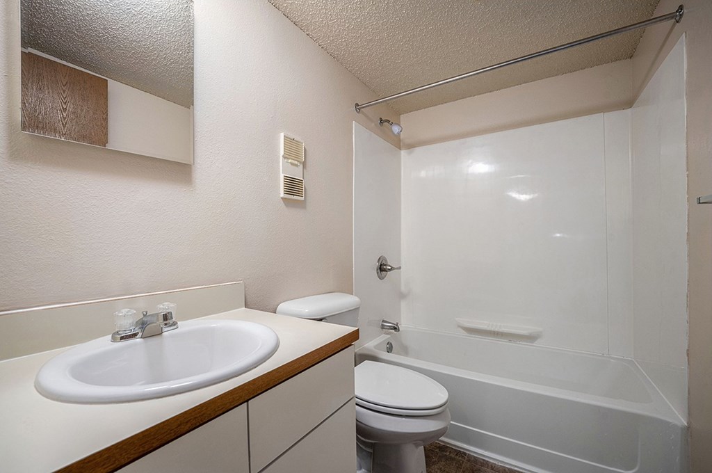 A toilet, sink, bathtub, and mirror in a bathroom at Seville Apartments, Michigan