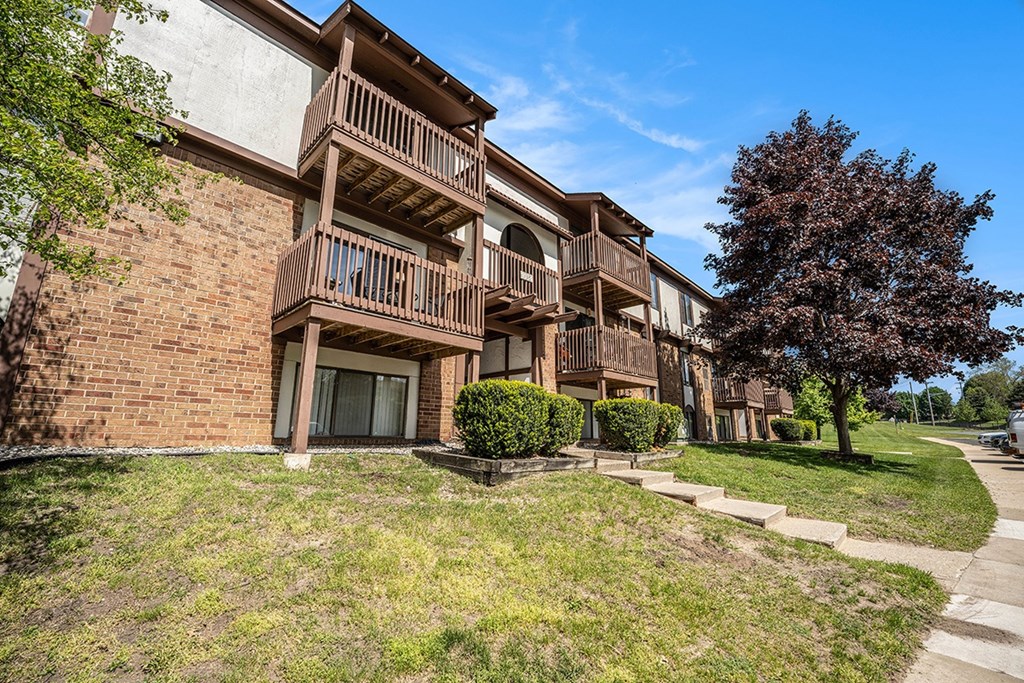 A large brick building with balconies overlooking a green lawn at Seville Apartments, Michigan