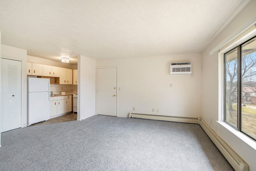 A spacious living room with a carpeted floor and a large window at Seville Apartments, Michigan