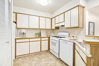 A kitchen with white appliances and wooden cabinets at South Bridge Apartments in Fort Wayne, IN