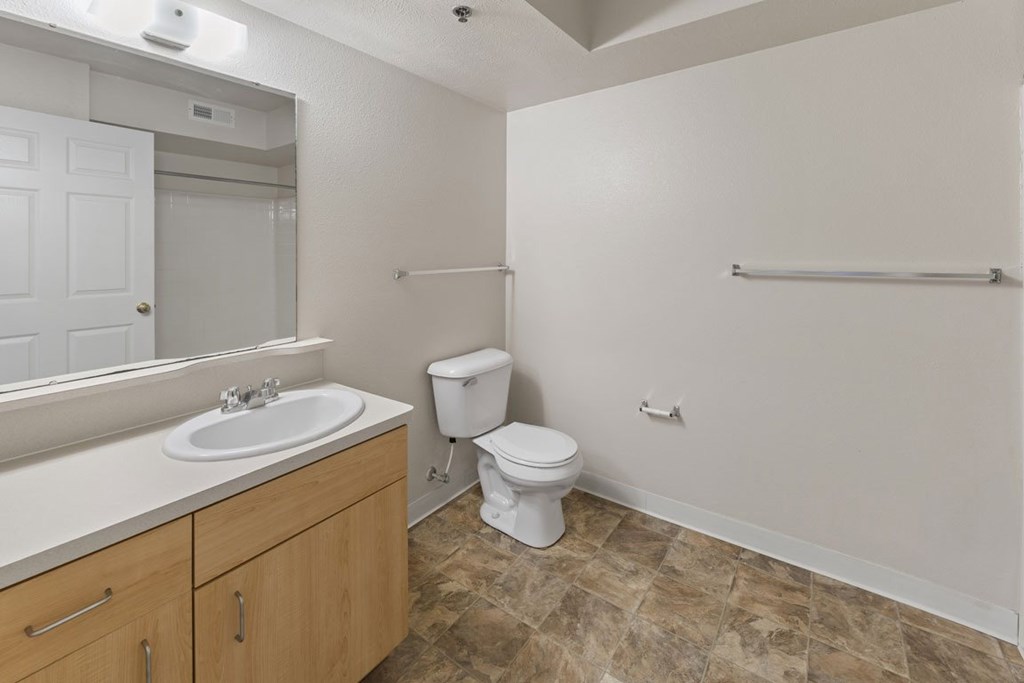 A bathroom with a toilet, sink, and mirror at Stoney Pointe Apartment Homes, Wichita