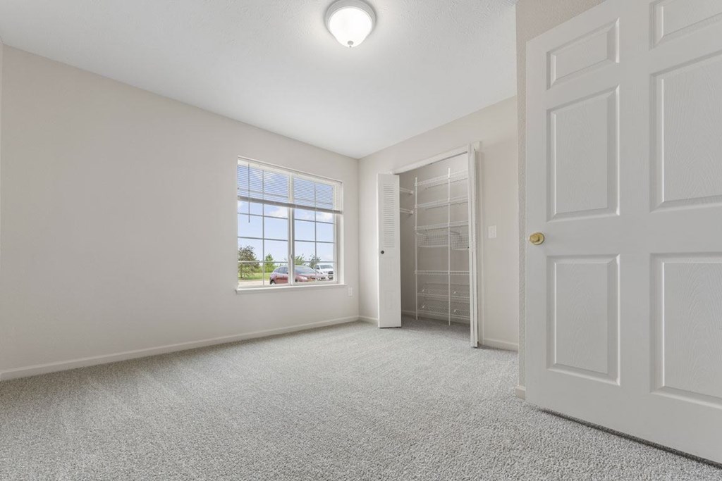 A bedroom with a window and a carpeted floor at Stoney Pointe Apartment Homes, Kansas
