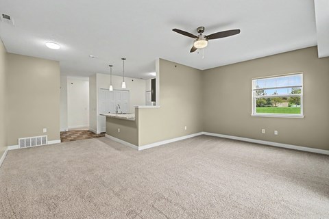 A spacious room with a ceiling fan and carpeted floor.