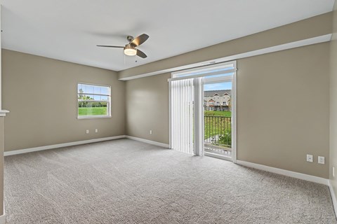 A room with a ceiling fan and sliding glass doors leading to a patio.