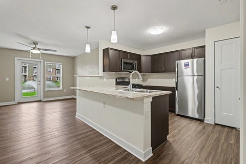 A kitchen with a refrigerator, microwave, and sink.