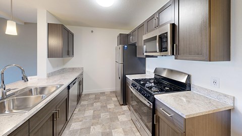 A kitchen with a stove, sink, and refrigerator.