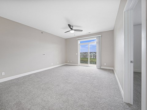 A room with a ceiling fan and a window with a view of a fence and trees.