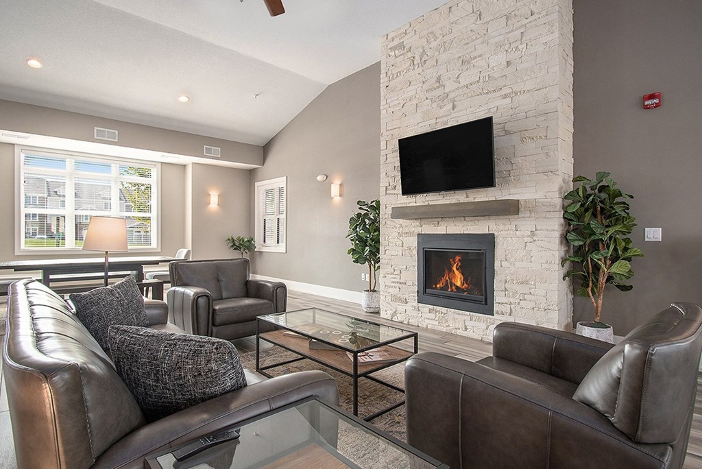 A community room with a fireplace and a television at Strathmore Apartment Homes, West Des Moines, IA