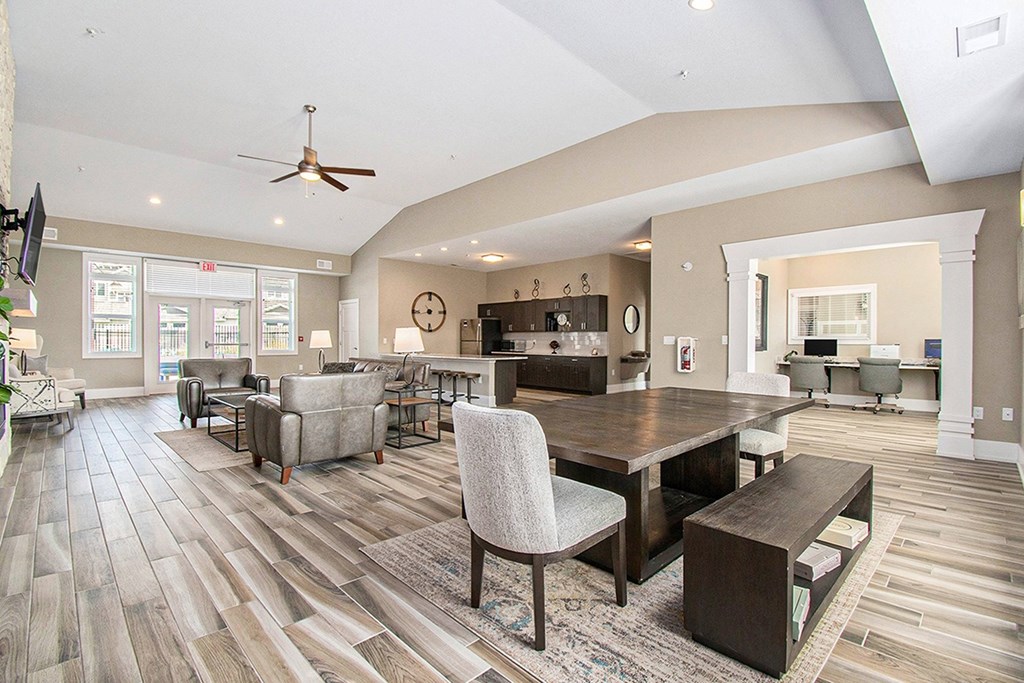 A spacious community room with a vinyl plank floor and a large table at Strathmore Apartment Homes, West Des Moines, IA