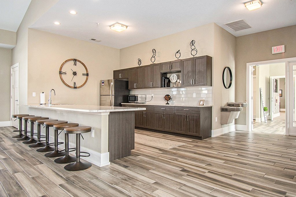 A kitchen with a bar area and a clock on the wall at Strathmore Apartment Homes, West Des Moines, IA