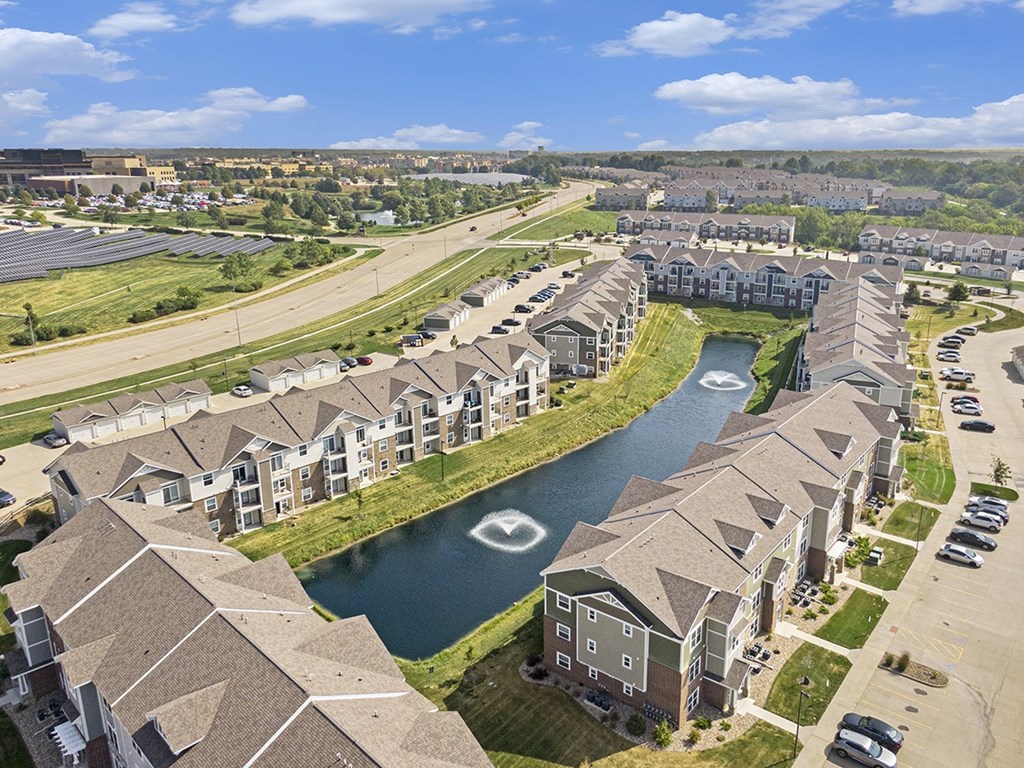 A large apartment complex with a pond in the middle at Strathmore Apartment Homes, West Des Moines, IA