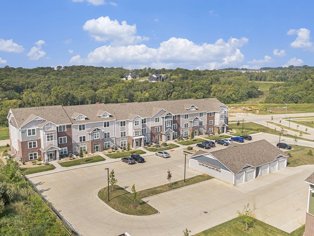 A large apartment building with a parking lot and garages in front at Strathmore Apartment Homes, West Des Moines, IA