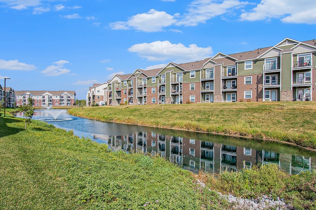 An apartment building is reflected in the water of a pond at Strathmore Apartment Homes, West Des Moines, IA