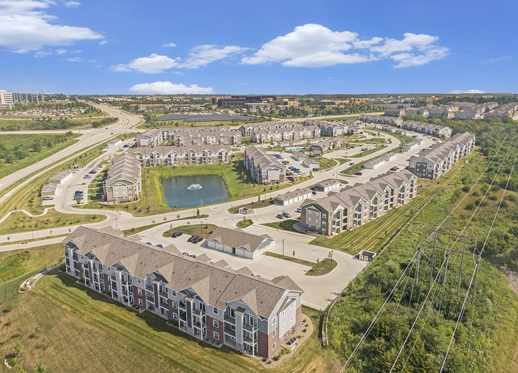 A large residential complex with multiple buildings and a central pond at Strathmore Apartment Homes, West Des Moines, IA