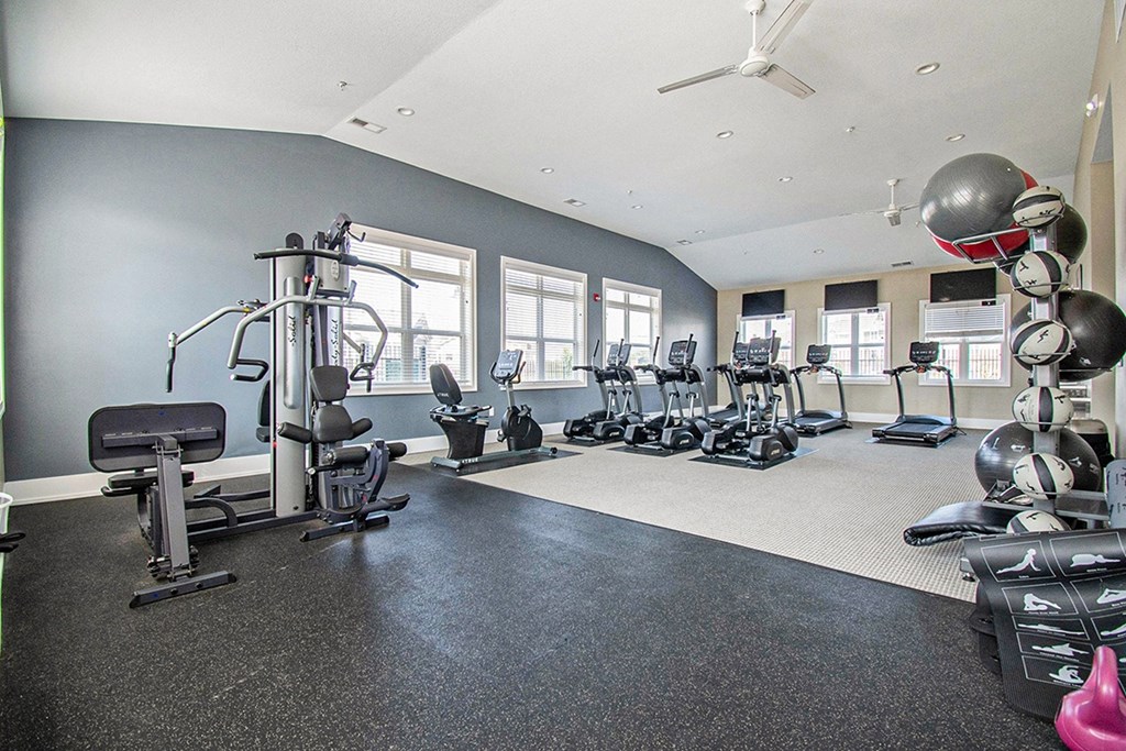 A spacious fitness center with a variety of equipment including treadmills, weights, and exercise machines at Strathmore Apartment Homes, West Des Moines, IA
