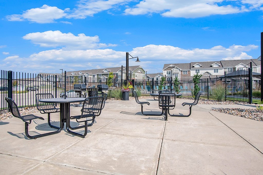 A concrete patio with grills, tables and chairs at Strathmore Apartment Homes, West Des Moines, IA