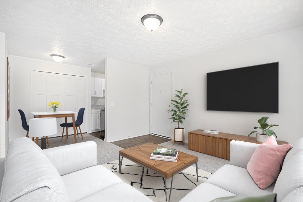 A living room with a white couch, a wooden coffee table, and a carpeted floor at Swiss Valley Apartments in Wyoming, MI