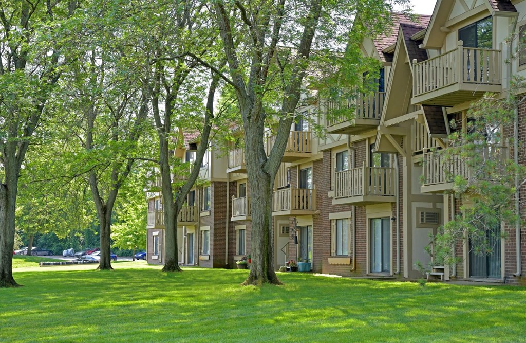 a large grassy area with trees in front of a building  at Sycamore Creek Apartments, Lake Orion