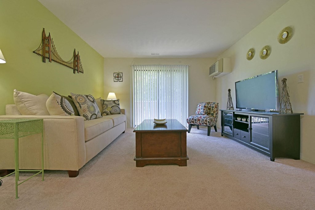 a living room with a couch coffee table and a television  at Sycamore Creek Apartments, Michigan
