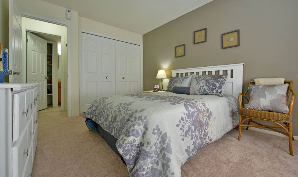 a bedroom with a bed and a dresser  at Sycamore Creek Apartments, Lake Orion