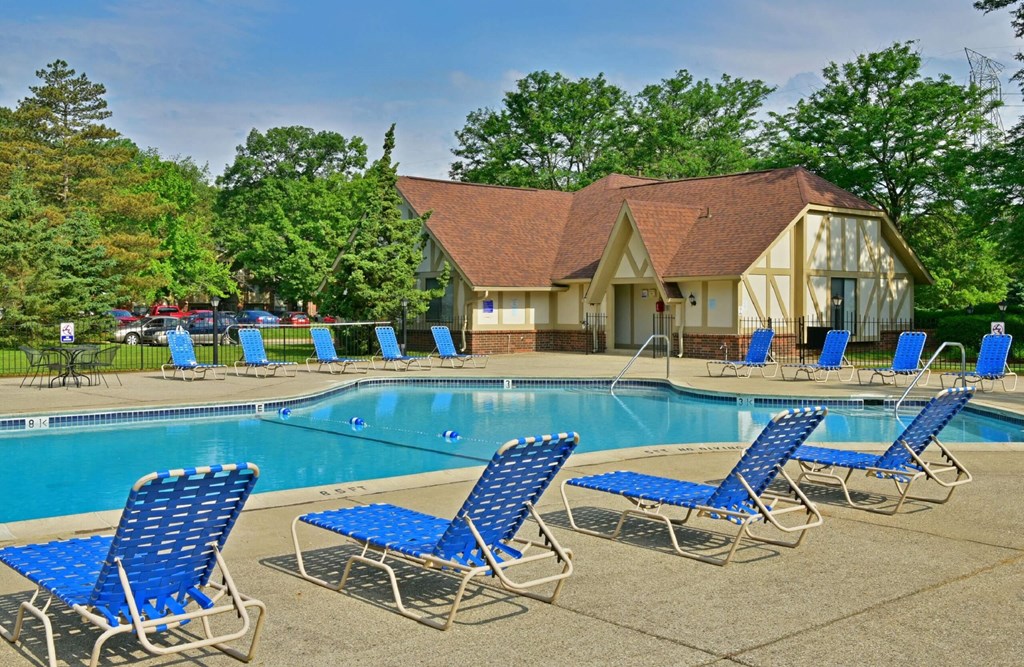 a swimming pool with chaise lounge chairs and a building in the background  at Sycamore Creek Apartments, Michigan, 48359