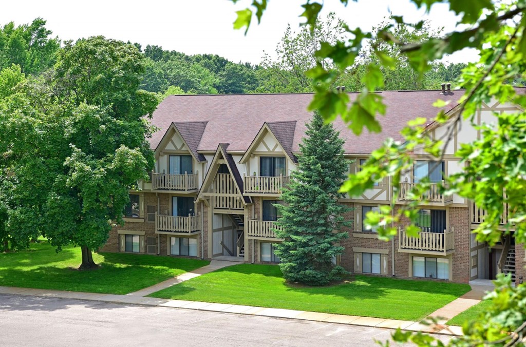 an exterior view of a large apartment building with trees in the foreground  at Sycamore Creek Apartments, Lake Orion, Michigan